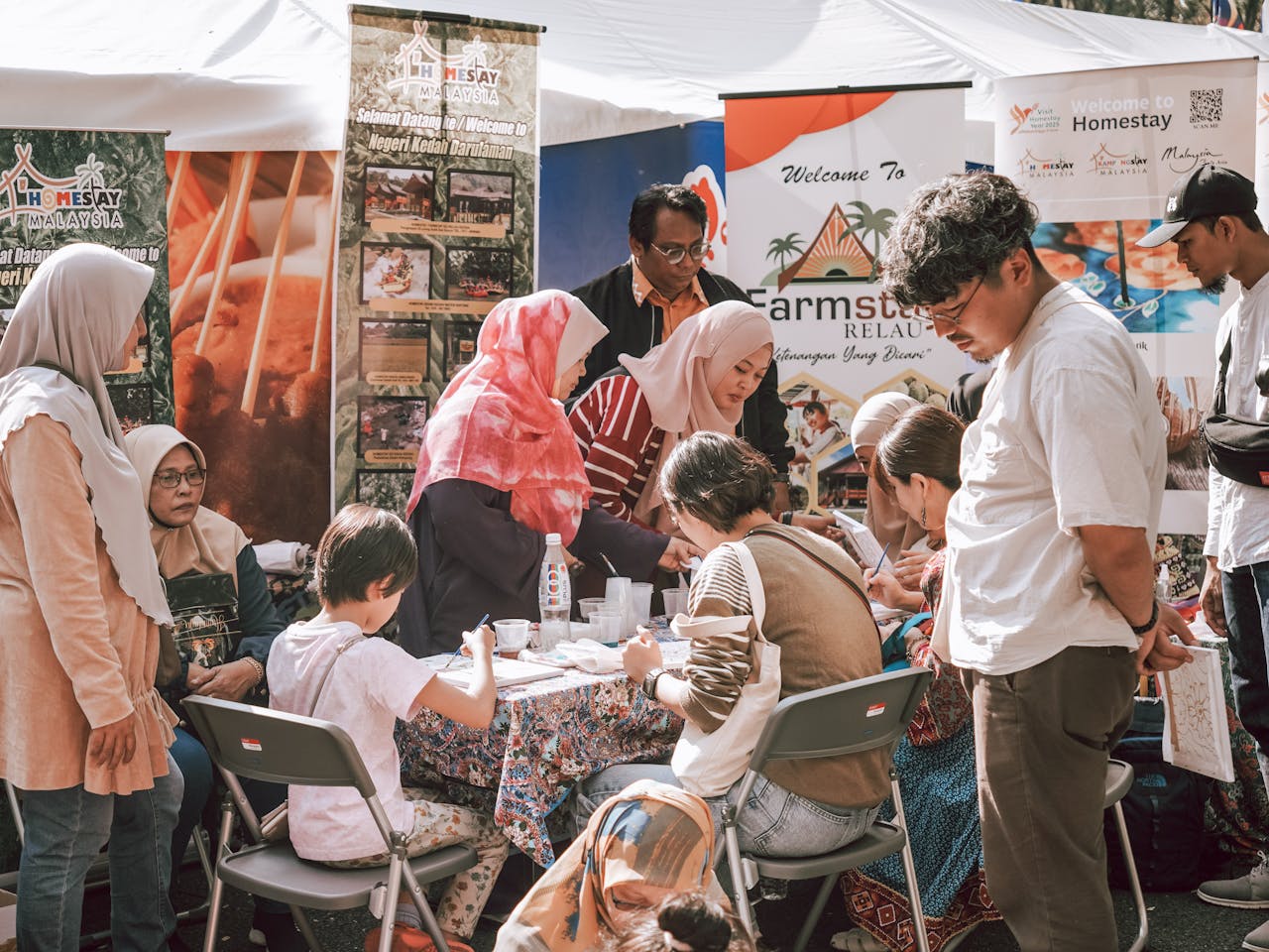 gallery-4 A diverse group of people engaged in activities at a cultural festival booth.