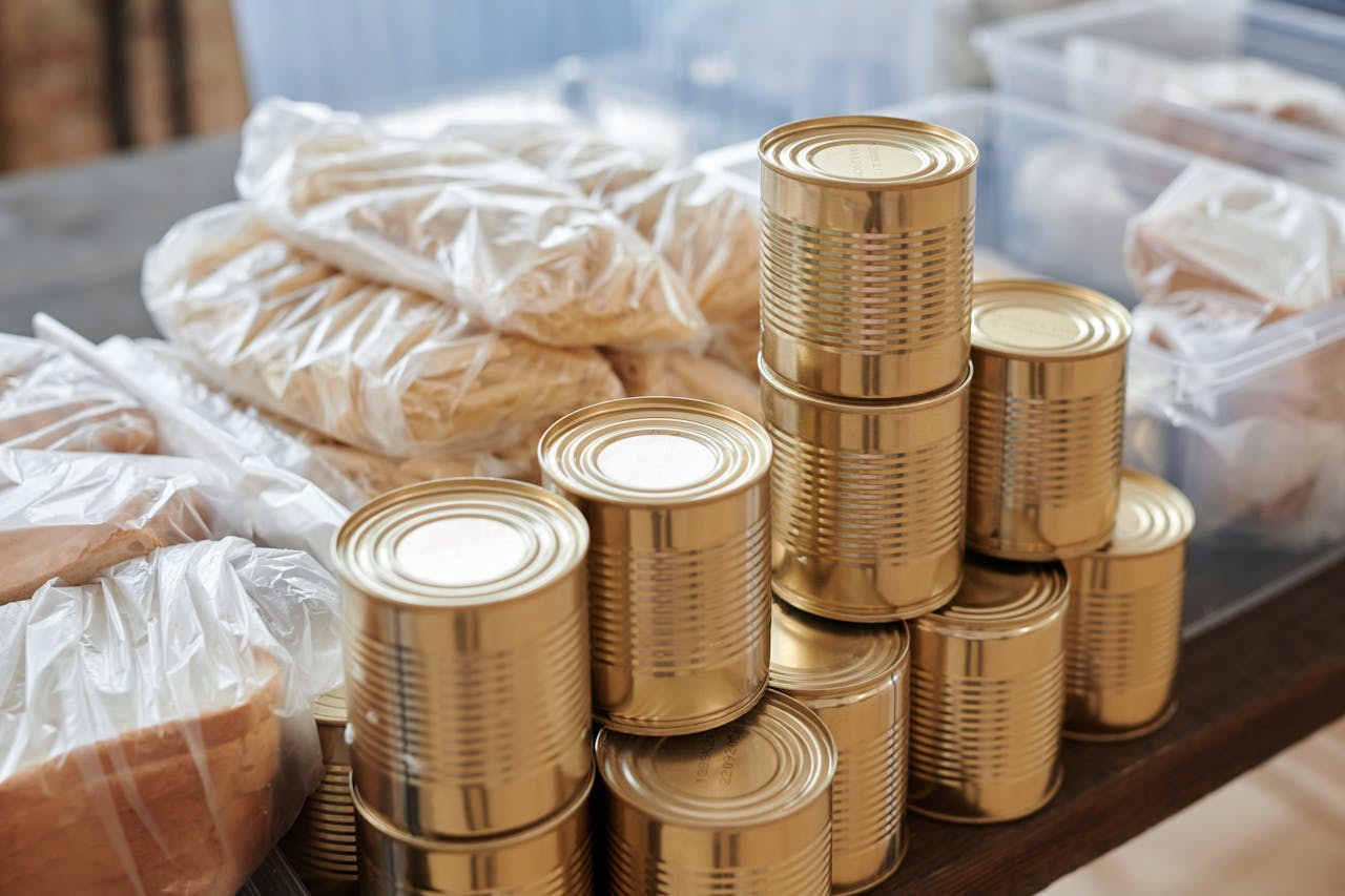 our-experience A stack of canned goods and packaged foods on a table, perfect for donation drives.